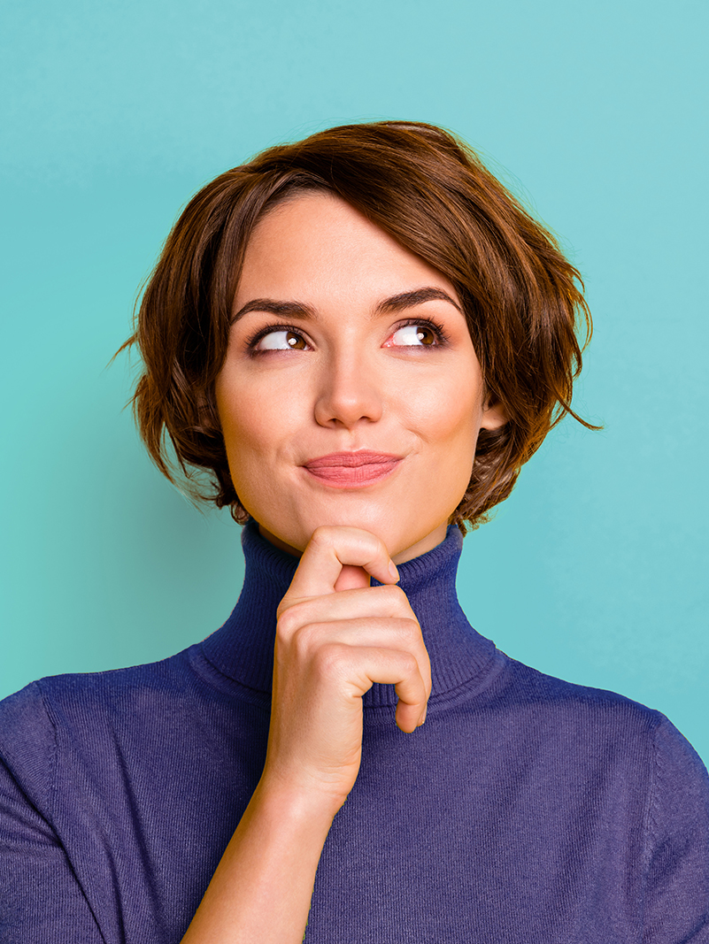 A woman holding her chin pensively with a whimsical smile on her face.